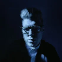 Et litt uklart fotografert portrett i blått og svart av kunstneren Carsten Aniksdal.